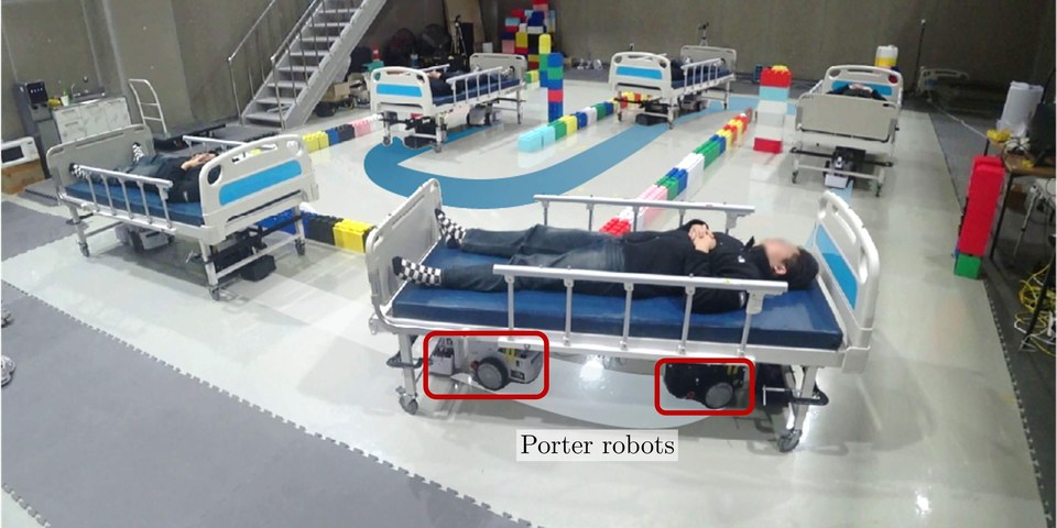Two porter robots cooperatively transporting a hospital bed through a cluttered test environment